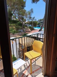 a yellow chair and a table on a balcony at Hostal Playa in Cala Santanyi