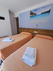 two beds in a hotel room with a picture on the wall at Hostal Playa in Cala Santanyi