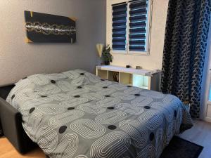 a bedroom with a bed with a comforter on it at Cosy Studio in Nogent-sur-Marne, City Centre, WiFi in Nogent-sur-Marne