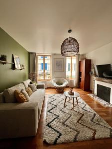 a living room with a couch and a rug at "Le Noeud vert" Appartement sur le thème de Nevers, 65 m2 en coeur de ville, parking à 200M avec accès inclus à salle de sport de 2000m2, Sauna & Hammam, by PRIMO C0NCIERGERIE in Nevers