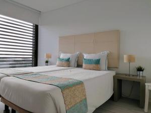 una camera da letto con un letto grande con lenzuola e cuscini bianchi di Silver Coast Heights H ad Areia Branca Altre 25 foto