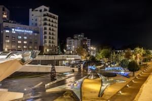Una calle de la ciudad por la noche con edificios y luces. en Queen Regina Suites, en Nicosia