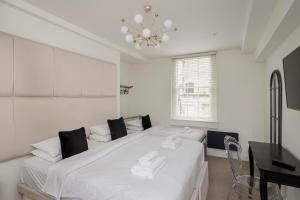 a white bedroom with a large bed and a chandelier at Luxury Home with Terrace in Central Bath Sleeps 10 in Bath