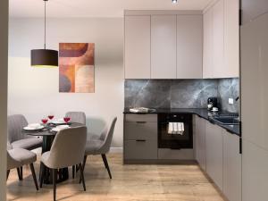una cocina con mesa y sillas y una cocina con armarios blancos. en URBAN APARTMENTS GLOBAL SKYLINE 18th Floor No 02 Free Garage, Self Check-in, No Deposit, en Katowice
