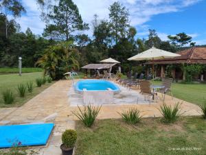 a swimming pool in a yard with chairs and an umbrella at Pousada dos Girassóis in Cunha