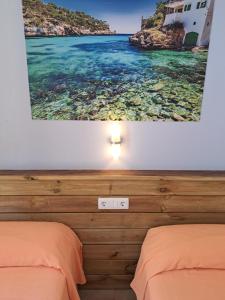 a bedroom with two beds and a picture of the ocean at Hostal Playa in Cala Santanyi