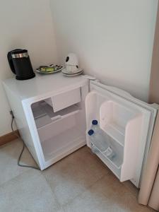 a small white refrigerator with its door open at Hostal Playa in Cala Santanyi