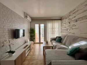 ein Wohnzimmer mit einer Couch und einem Fernseher an einer Ziegelwand in der Unterkunft Apartamento Luz de Buda in Mijas Costa