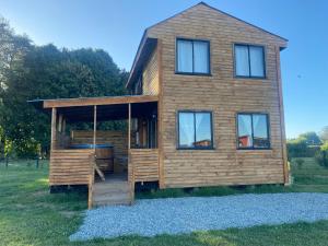 a log cabin with a deck and a house at El Encanto de Antilhue in Valdivia