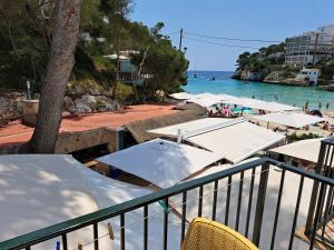 a view of a beach with umbrellas and the ocean at Hostal Playa in Cala Santanyi
