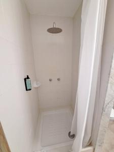 a white shower with a shower curtain in a bathroom at Hostal Playa in Cala Santanyi