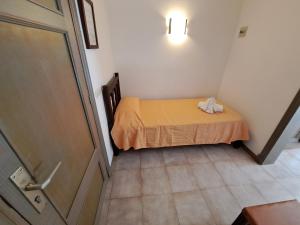a small room with a bed with a yellow blanket at Hostal Playa in Cala Santanyi