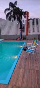 an umbrella and two chairs next to a swimming pool at Kitnet privada confortável em Pontal do Sul in Pontal do Paraná