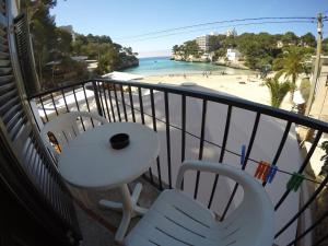 a balcony with a table and chairs and a beach at Hostal Playa in Cala Santanyi