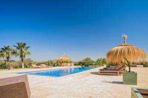un complexe avec une piscine et des parasols en paille dans l'établissement Flor de Sal a Sa Canoveta by Bebreeze, à Campos