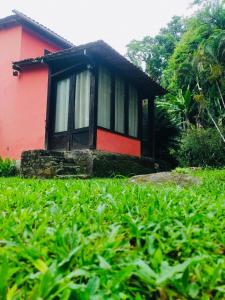 a small red and black house in a field of grass at Pouso in Paraty