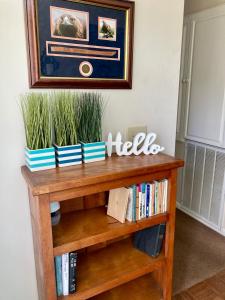 a wooden book shelf with books and plants on it at Rose's House in Lanett