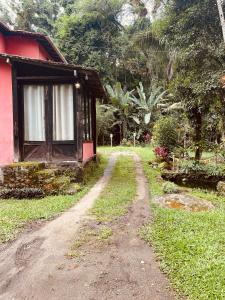 a dirt road next to a red house with a window at Pouso in Paraty