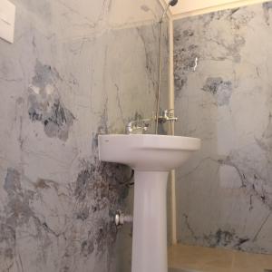 a white sink in a bathroom with a marble wall at Hotel RICHMOND Punta del Este in Punta del Este
