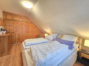 a large bed in a room with wooden cabinets at Ferienhaus Holly-Day in Dornum