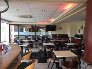 a restaurant with tables and chairs and a flat screen tv at Grange Gardens Hotel in Durban
