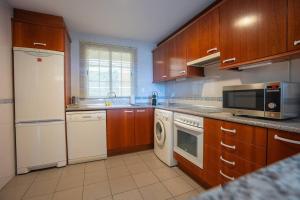 a kitchen with wooden cabinets and white appliances at Espacioso apartamento en Mijas con parking privado in Sitio de Calahonda