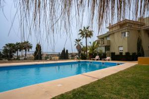 a swimming pool in front of a house at Espacioso apartamento en Mijas con parking privado in Sitio de Calahonda