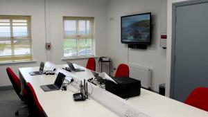 a conference room with two tables and chairs with laptops at Teach Greannaí Cabin in Curraunboy