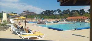 a swimming pool with people sitting in lounge chairs near it at camping les oyats in Seignosse