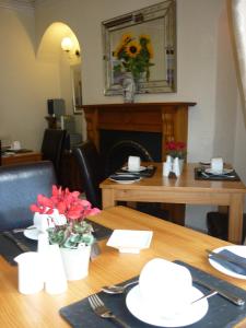 a dining room table with a wooden table with flowers on it at All Seasons Guest House in Windermere