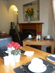 una mesa de comedor con una mesa de madera con flores. en All Seasons Guest House, en Windermere