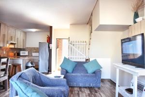 a living room with two blue chairs and a tv at Beachfront Selfcatering in Hentiesbaai