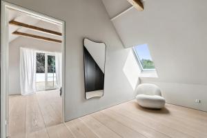 Cette chambre blanche dispose d'un miroir et d'une chaise blanche. dans l'établissement Elegant Luxury Villa in the Heart of Aarhus, à Aarhus