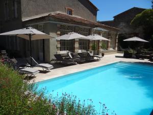 a swimming pool with chairs and umbrellas next to a building at Bed & Breakfast L'Orangerie in Carcassonne