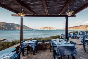 a patio with tables and chairs and a view of the ocean at Phāea Blue - Small Luxury Hotels of the World in Elounda