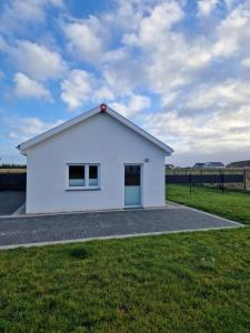 Ein weißes Haus auf einem Grasfeld mit einem Himmel in der Unterkunft Haus Noah in Sierosław