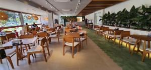 a restaurant with wooden tables and chairs in a room at Malia Beach Experience - Studios em Muro Alto por Yolo in Ipojuca +143 photos