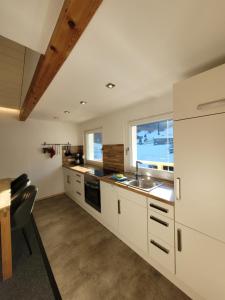 a kitchen with white cabinets and a sink at Haus Idili in Sankt Gallenkirch