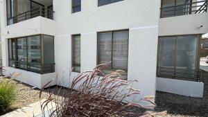 a white building with black windows and some plants at Departamento in Antofagasta