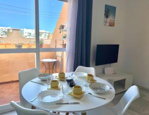a white dining room table with white chairs and a window at Ático centro Tarifa in Tarifa