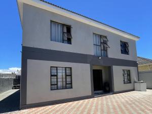 a white house with black windows and a driveway at Adiel Guesthouse in Cape Town