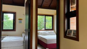 a small room with a bed and two windows at Residencial Martins in Bombinhas