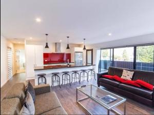 a living room with a couch and a kitchen at Central Spa Getaway (F2) in Queenstown