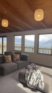 ein Wohnzimmer mit einer Couch und einigen Fenstern in der Unterkunft Lakeview Treehouse at Queenstown Hill in Queenstown + 14 Fotos