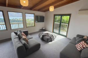 ein Wohnzimmer mit 2 Sofas und einer Ottomane in der Unterkunft Lakeview Treehouse at Queenstown Hill in Queenstown