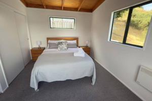 ein Schlafzimmer mit einem großen weißen Bett mit einem Fenster in der Unterkunft Lakeview Treehouse at Queenstown Hill in Queenstown