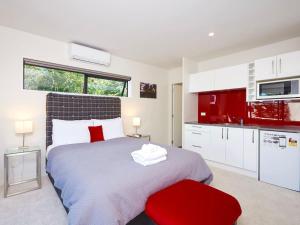 Un dormitorio con una cama grande y una silla roja. en Central Spa Getaway Studio (F1), en Queenstown