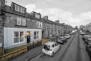 a street with a row of houses and parked cars at The Lang Toun Bothy - close to Edinburgh by Urban Haggis Stays in Kirkcaldy