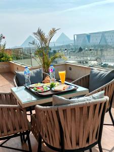Kush Hotel, Grand Museum & Pyramids View في القاهرة: طاولة مع طبق من الطعام على شرفة