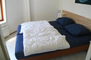 a bed with a blue blanket and two pillows on it at Heggerank 54 in Nieuwvliet